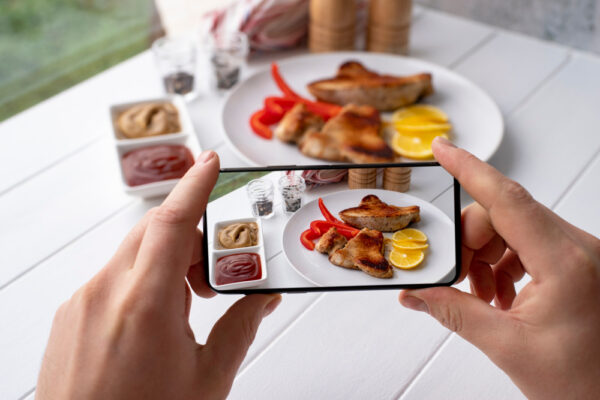 Persoană fotografiază farfurie cu carne și lămâie
